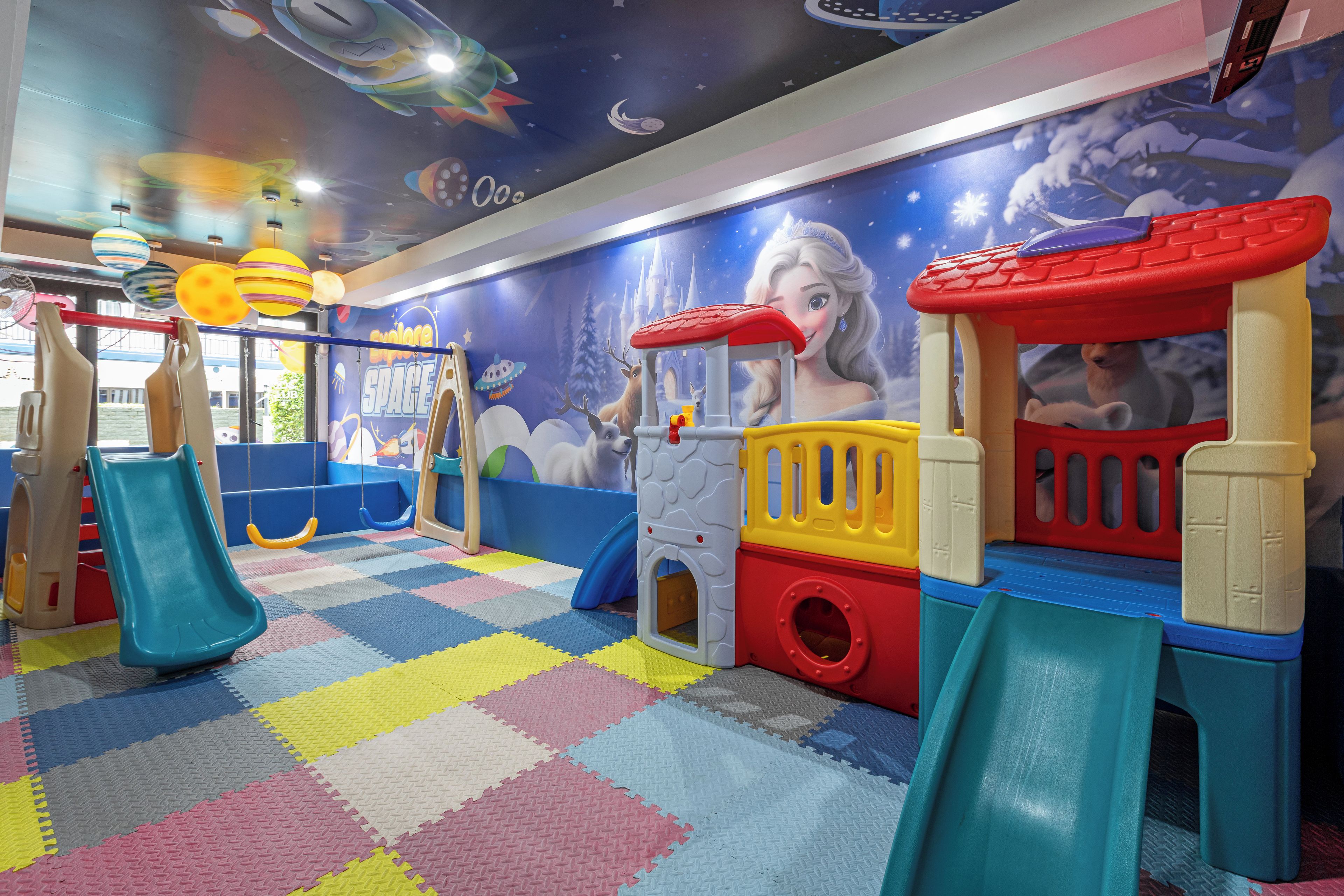 Un espace de jeux pour enfants avec un toboggan, des structures de jeu et une fresque murale.