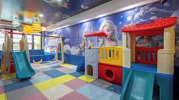 Zona de juegos infantiles con un tobogán, estructuras de juego y un mural.