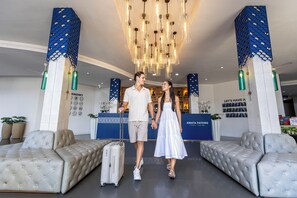 Eine Hotellobby mit einer Rezeption, einer Sitzecke und einem Chandelier.
