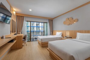 Une chambre d’hôtel avec deux lits, un bureau, une chaise, une télévision et un balcon donnant sur des immeubles.