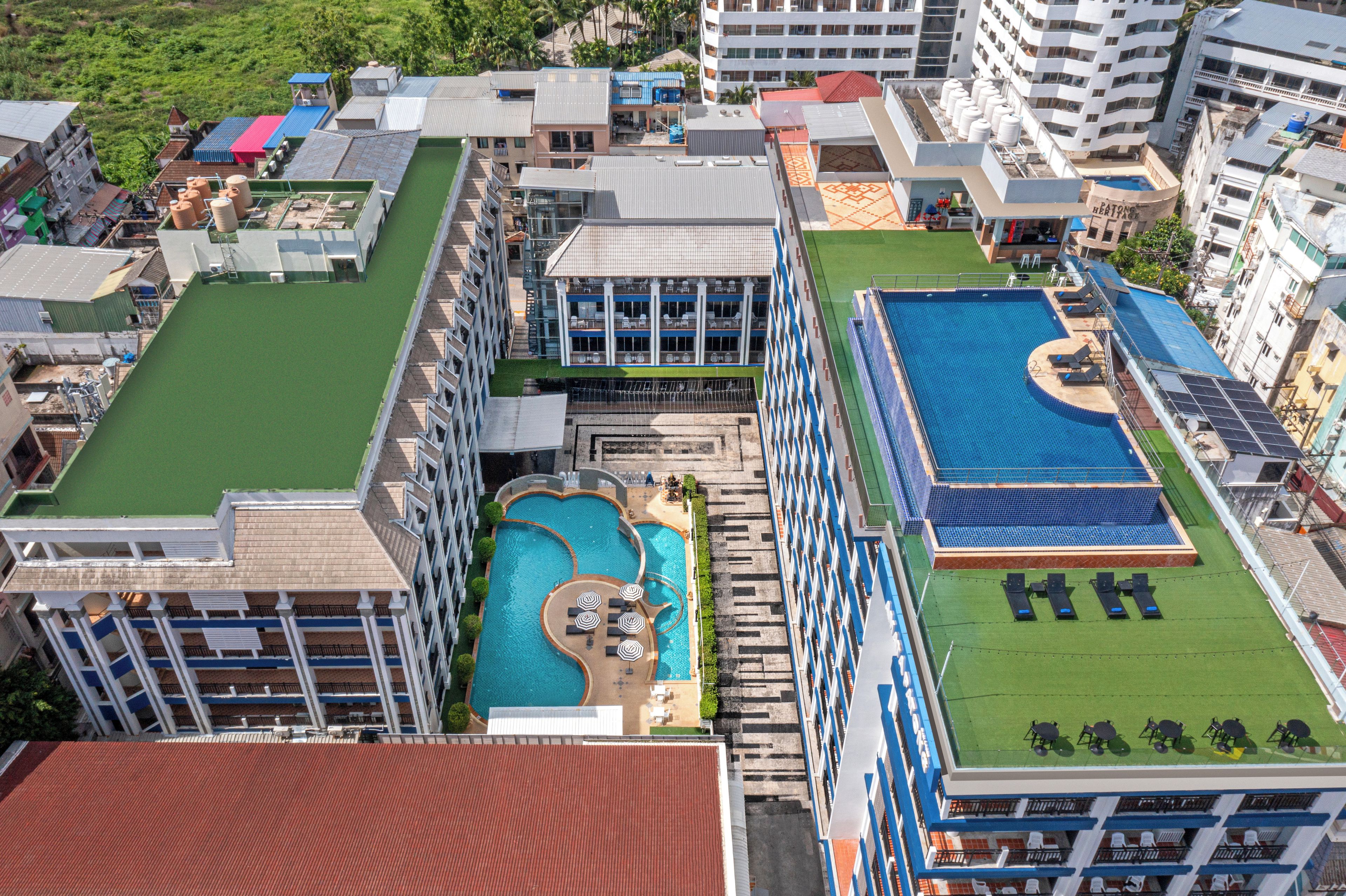 Ein Resort mit mehreren Schwimmbecken, einem Tennisplatz und verschiedenen Gebäudestilen.