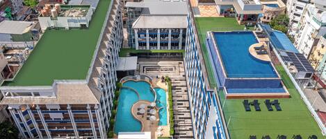 Ein Resort mit mehreren Schwimmbecken, einem Tennisplatz und verschiedenen Gebäudestilen.