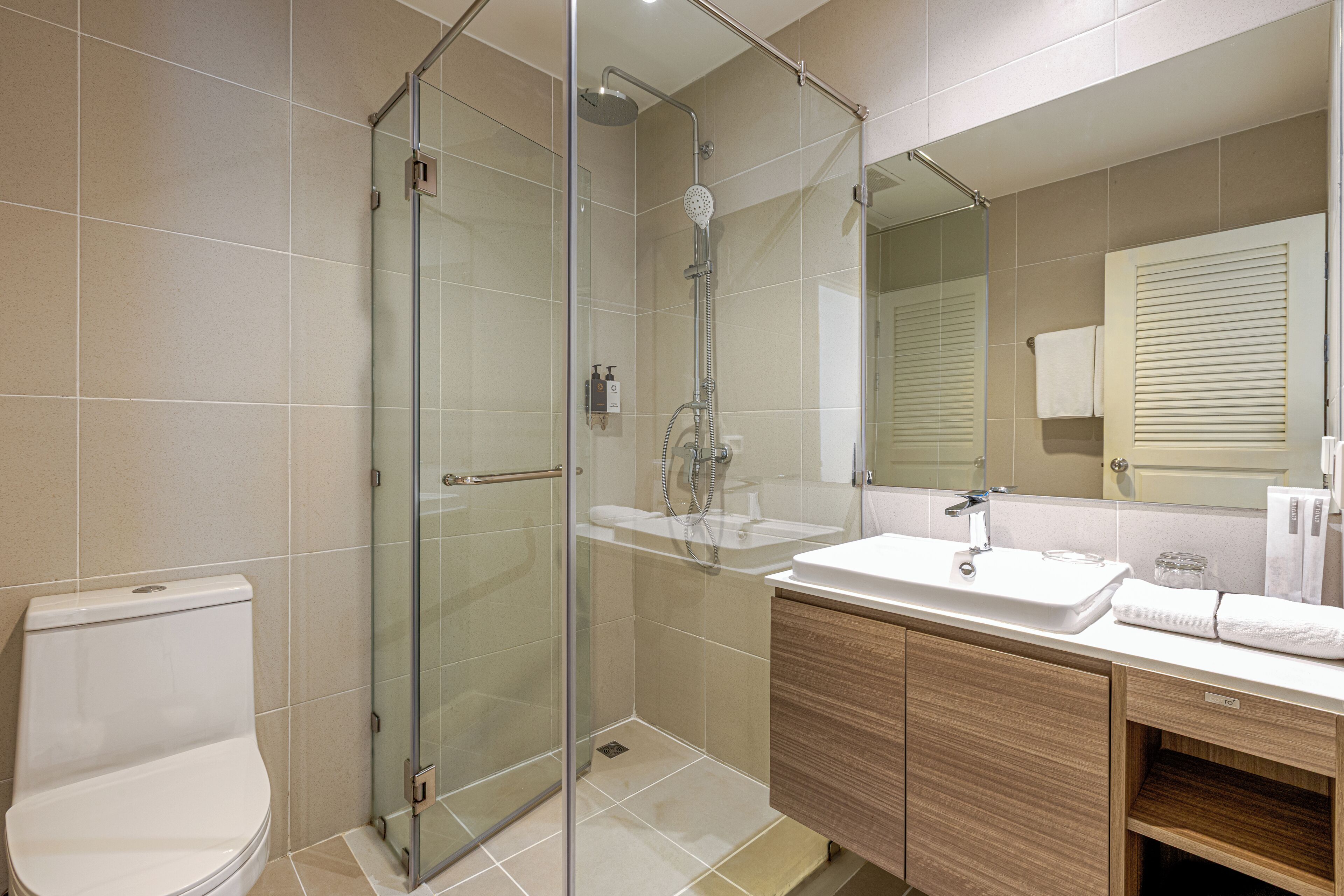 A modern bathroom with a glass-enclosed shower, a white sink, and a wooden vanity.