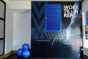 A gym wall with motivational posters, exercise balls, and a blue door. - Amata Patong (Patong)