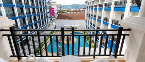 Un balcón con vista a la piscina, sillas de plástico blanco y barandilla.