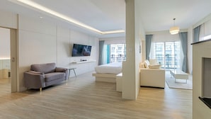 A modern hotel room with a flat-screen TV, a sofa, a bed, and a balcony with a view of the city. - Amata Patong (Patong)