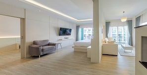 A modern hotel room with a flat-screen TV, a sofa, a bed, and a balcony with a view of the city.