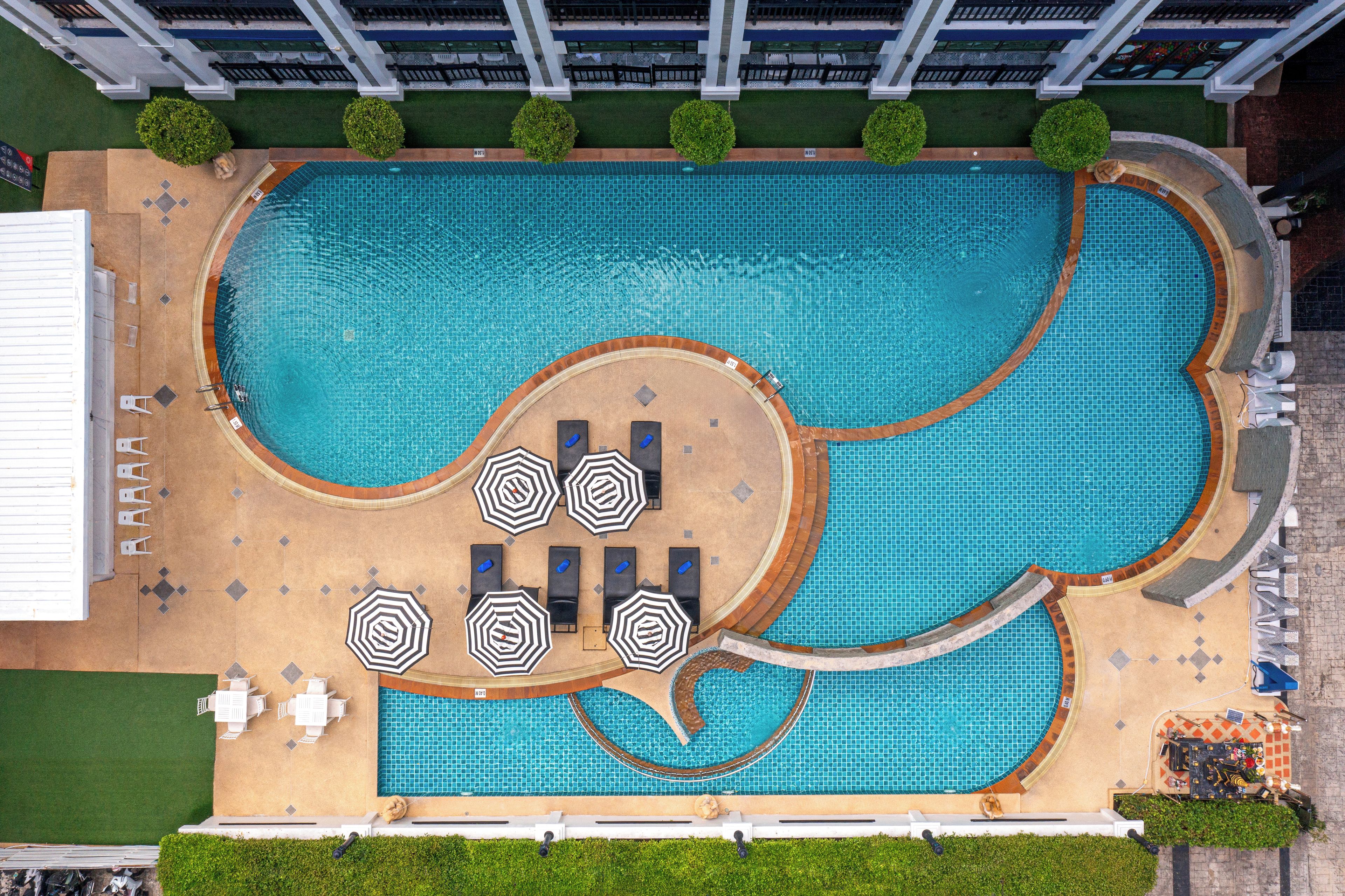 An aerial view of a swimming pool with multiple lounge areas and sunbeds.
