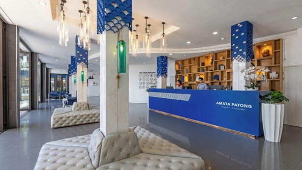 A modern reception area with a blue reception desk, seating, and a decorative ceiling. - Amata Patong (Patong)