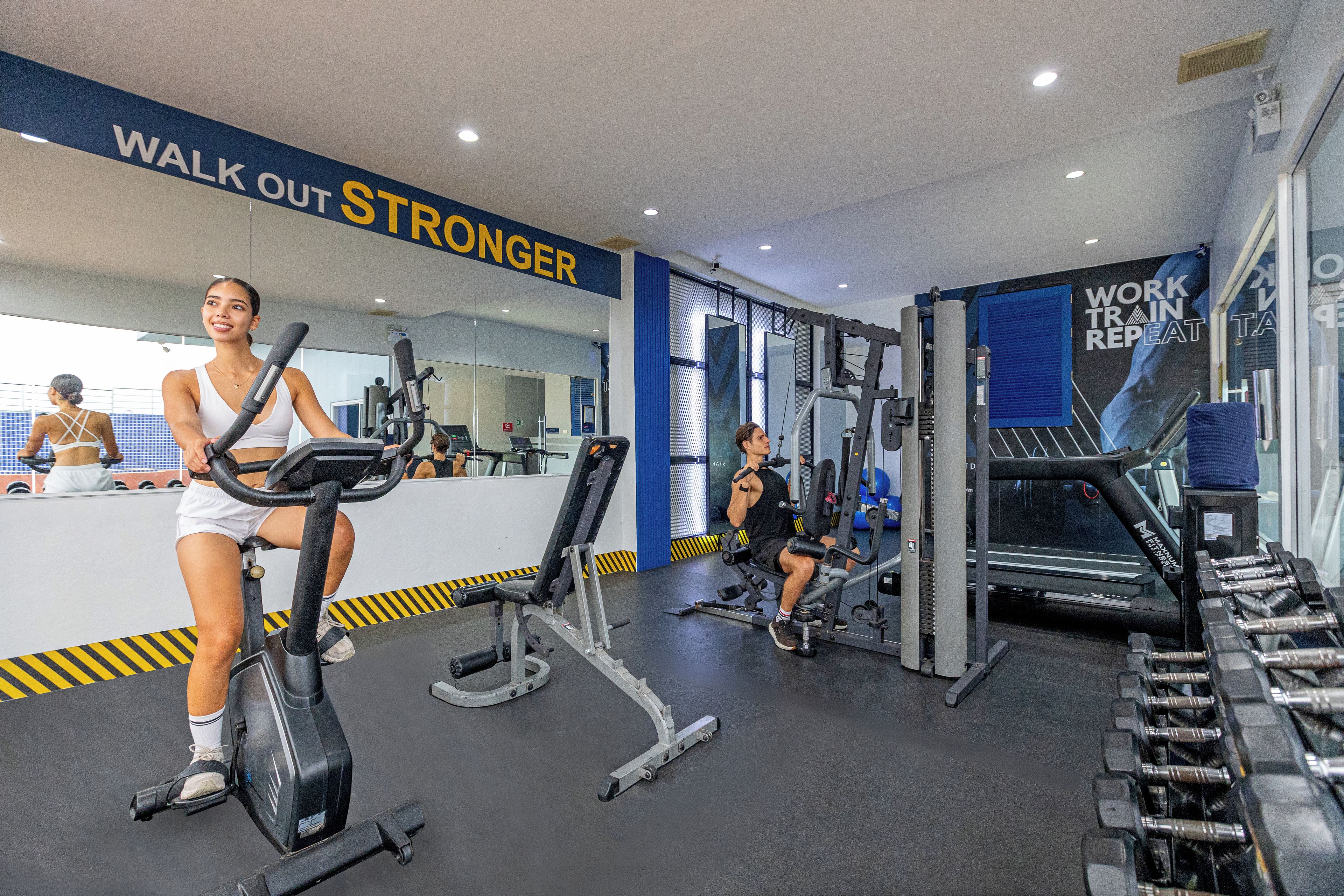 A gym with exercise equipment, a treadmill, and a wall with motivational text.
