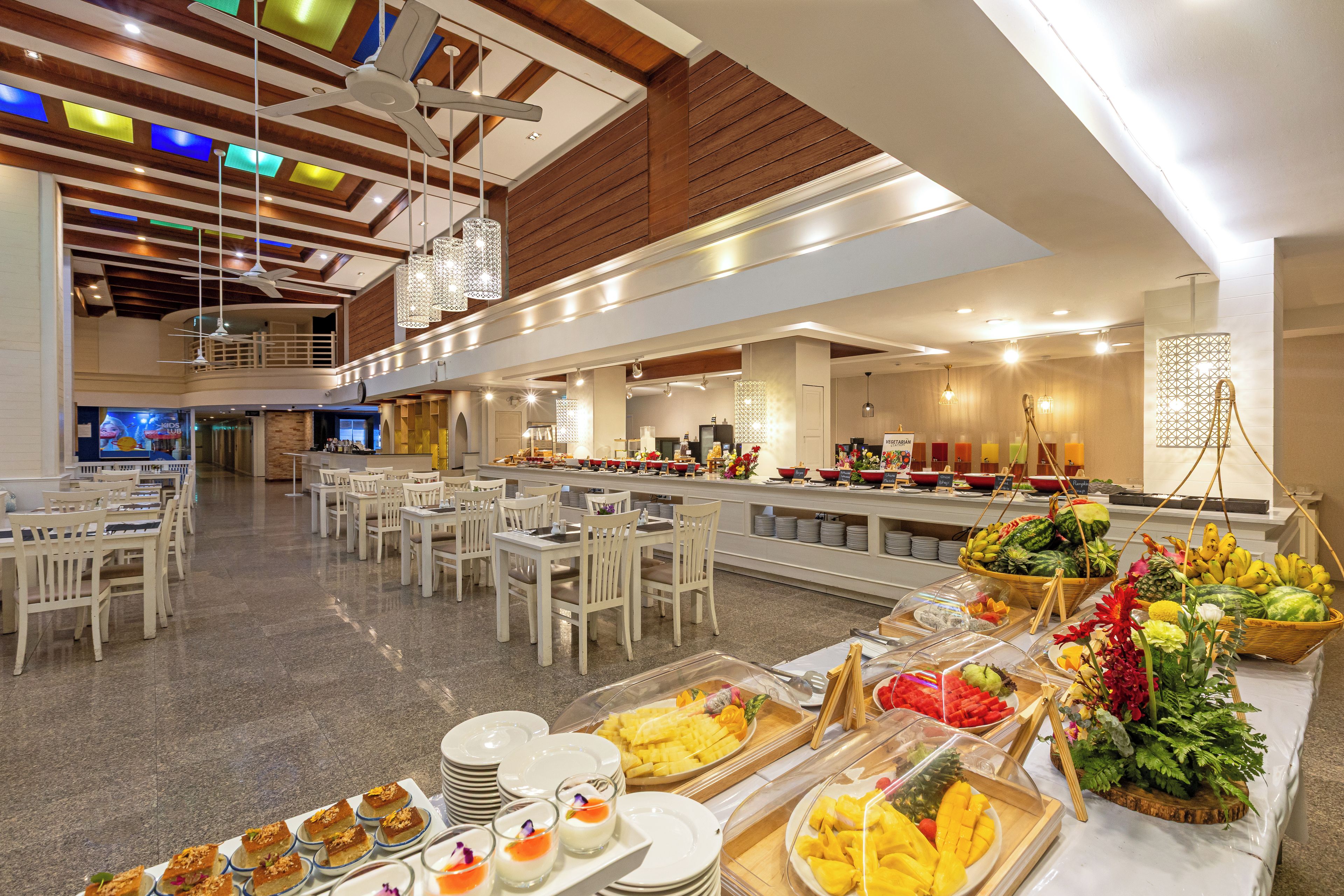A buffet area with various food options, seating arrangements, and a high ceiling with wooden beams.
