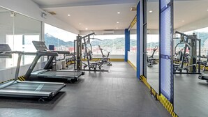 A gym with treadmills, weight machines, and a large window offering a view of a mountainous landscape. - Amata Patong (Patong)