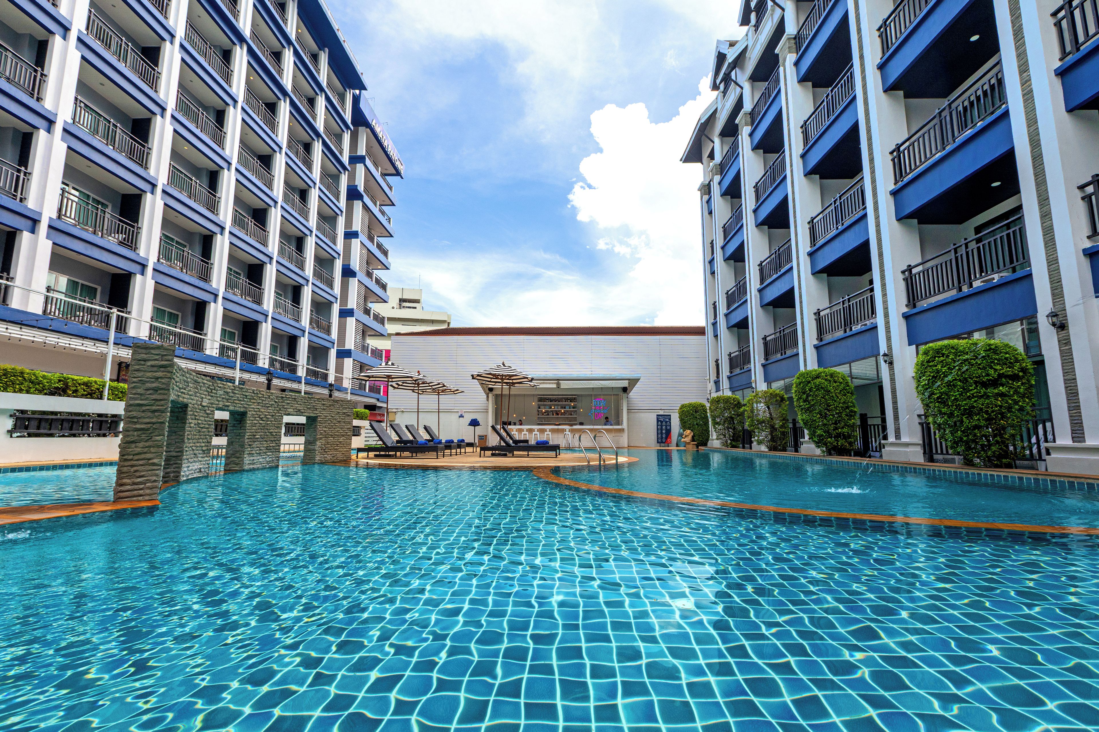 A hotel pool area with multiple balconies and a bar.
