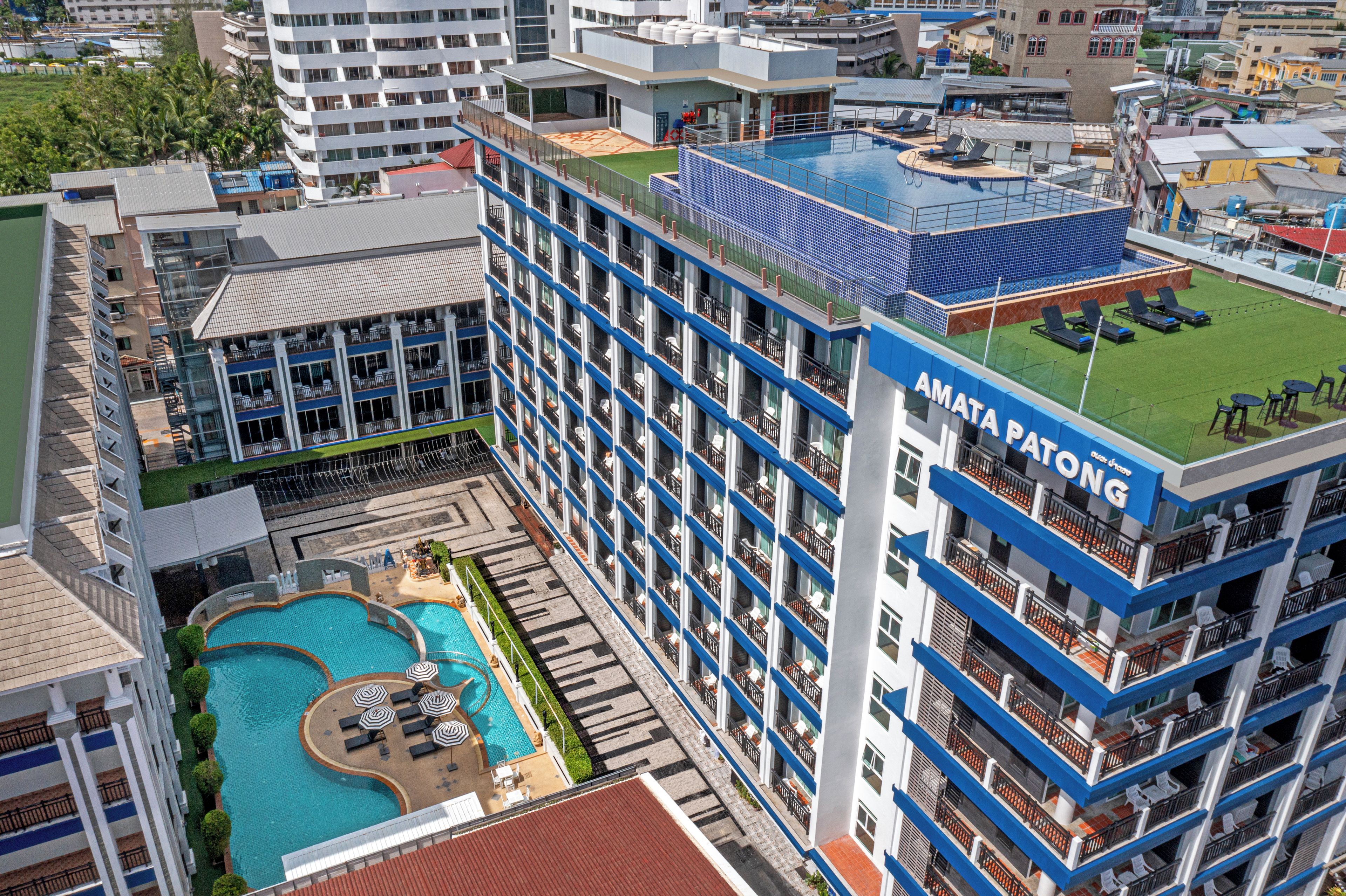 A multi-story hotel with a rooftop pool and a swimming pool on the ground level.