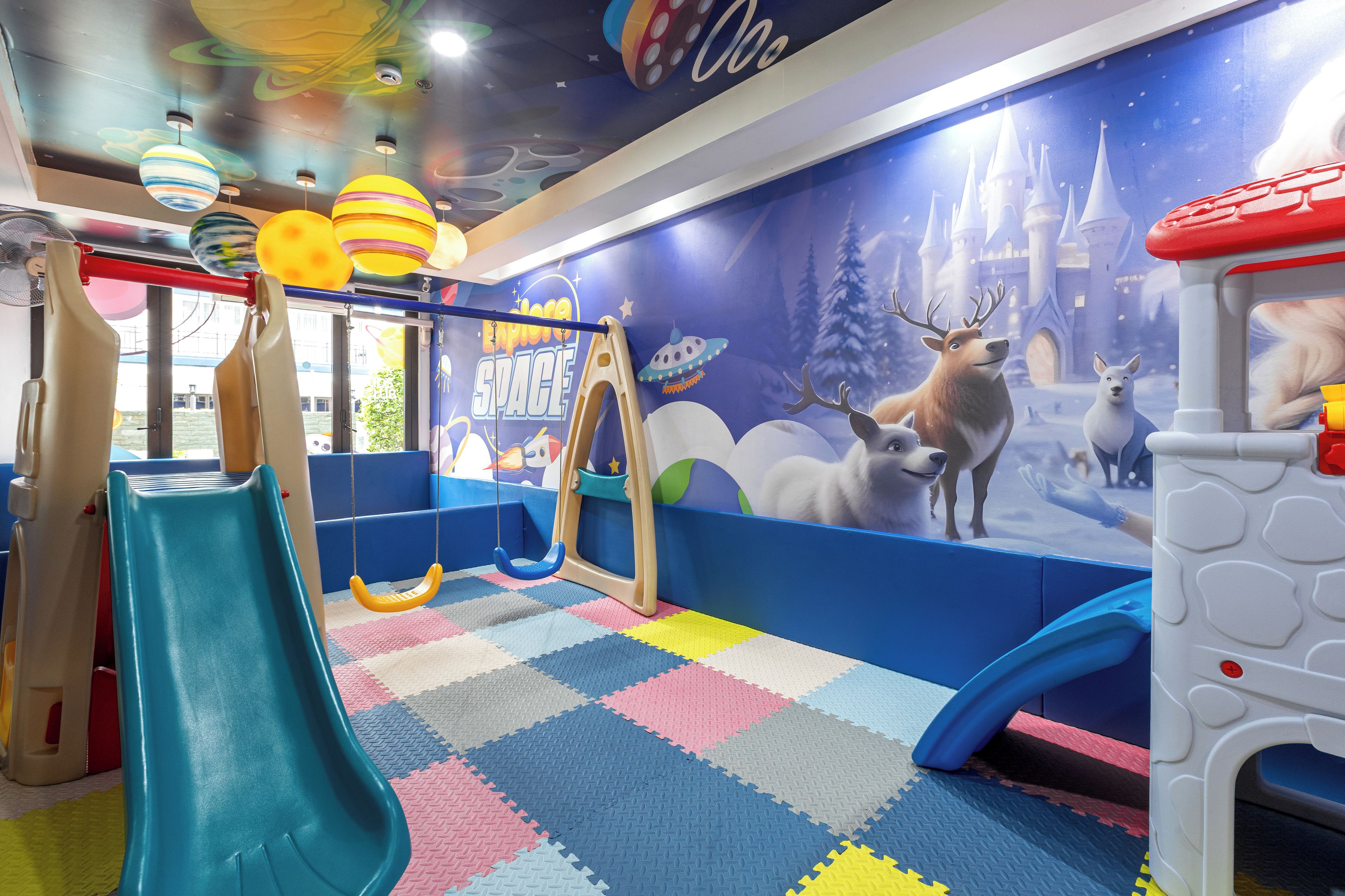 A children's play area with a slide, swings, and a wall mural.