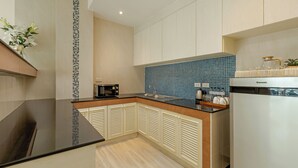A modern kitchen with a black countertop, a microwave, and a sink. - Amata Patong (Patong)