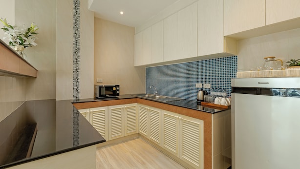 A modern kitchen with a black countertop, a microwave, and a sink. - Amata Patong (Patong)