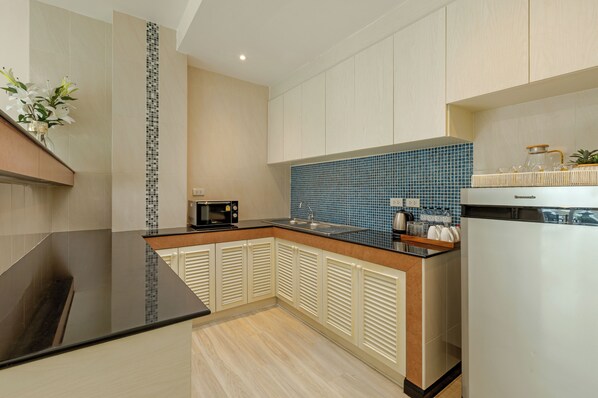 A modern kitchen with a black countertop, a microwave, and a sink. - Amata Patong (Patong)