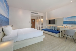 Una habitación de hotel con cama, escritorio, sillón, sofá y televisor.