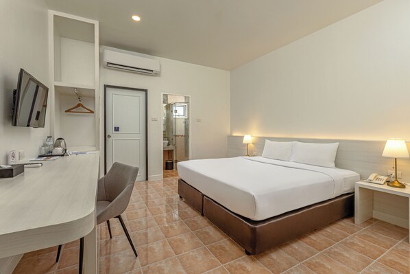 A hotel room with a bed, bedside table, chair, desk, and a television.