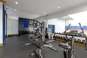 Une salle de sport équipée de matériel d’exercice, d’un banc et d’un mur orné de messages motivants.
