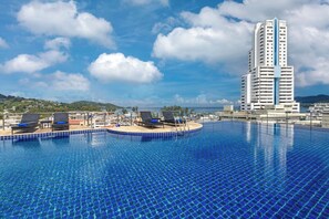A swimming pool with lounge chairs and a view of a tall building in the background.