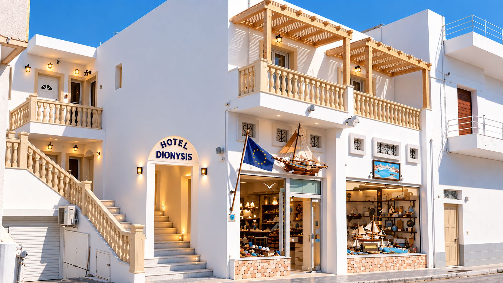 Un hotel llamado 'HOTEL DIONYSIS' con una escalera que conduce a la entrada, un balcón con barandillas de madera y una tienda con artículos de temática náutica.