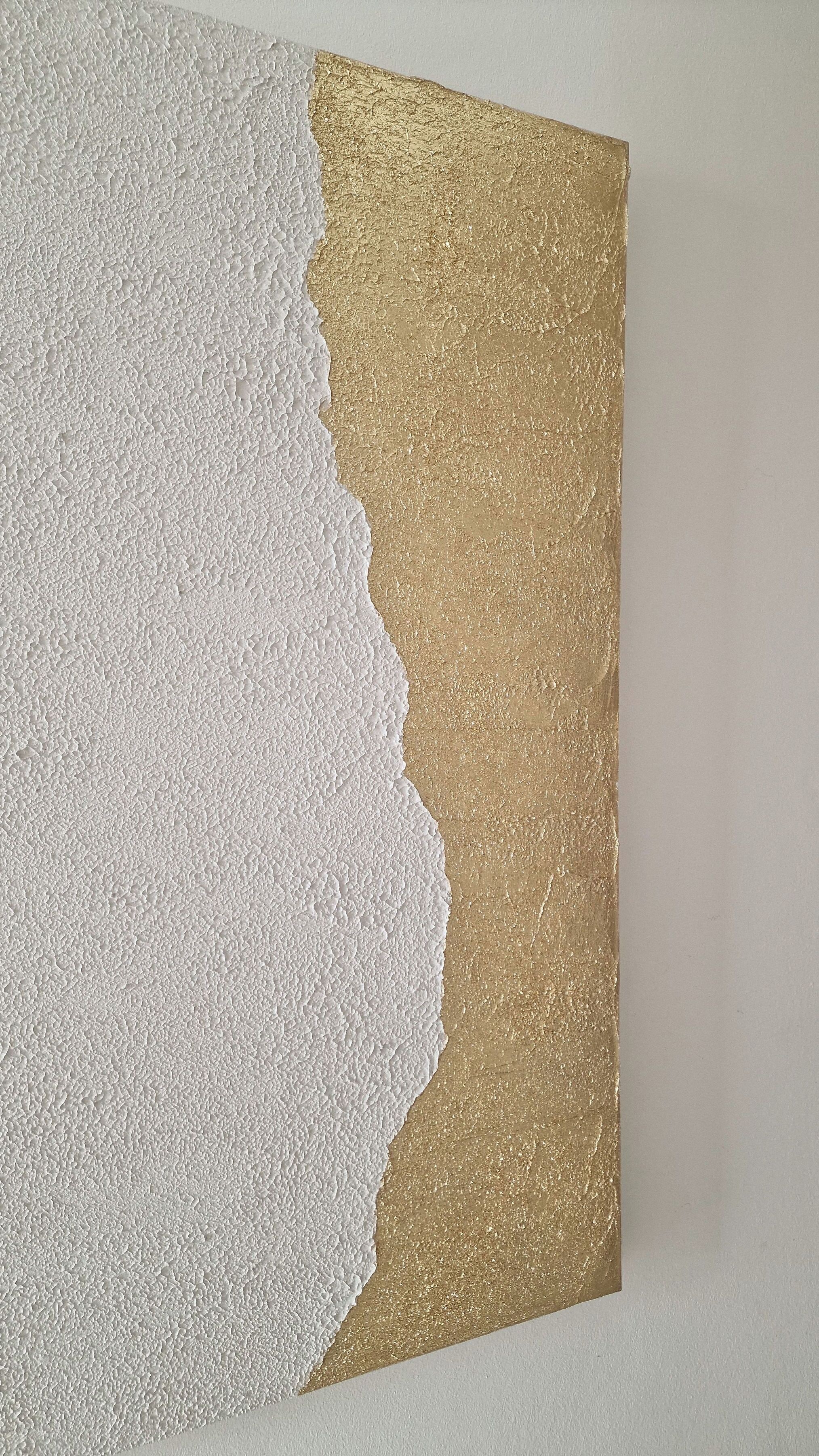 Een structuurwand met een wit en goud gedeelte.