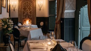 A dining area with a table set for four, candles, and a decorative wall. - Le Farnatchi (Marrakech)