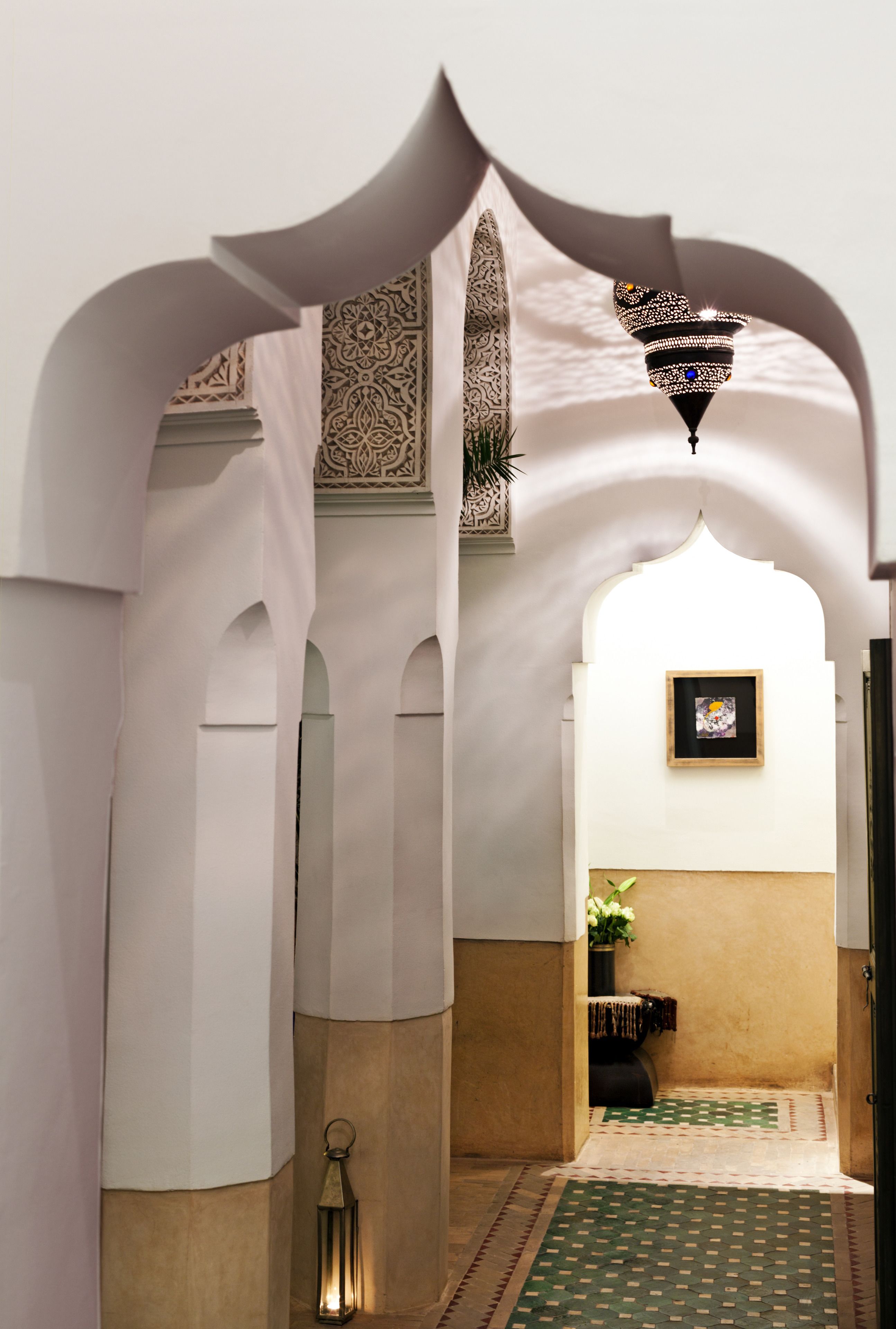 An arched hallway with patterned wall designs and a hanging lantern.