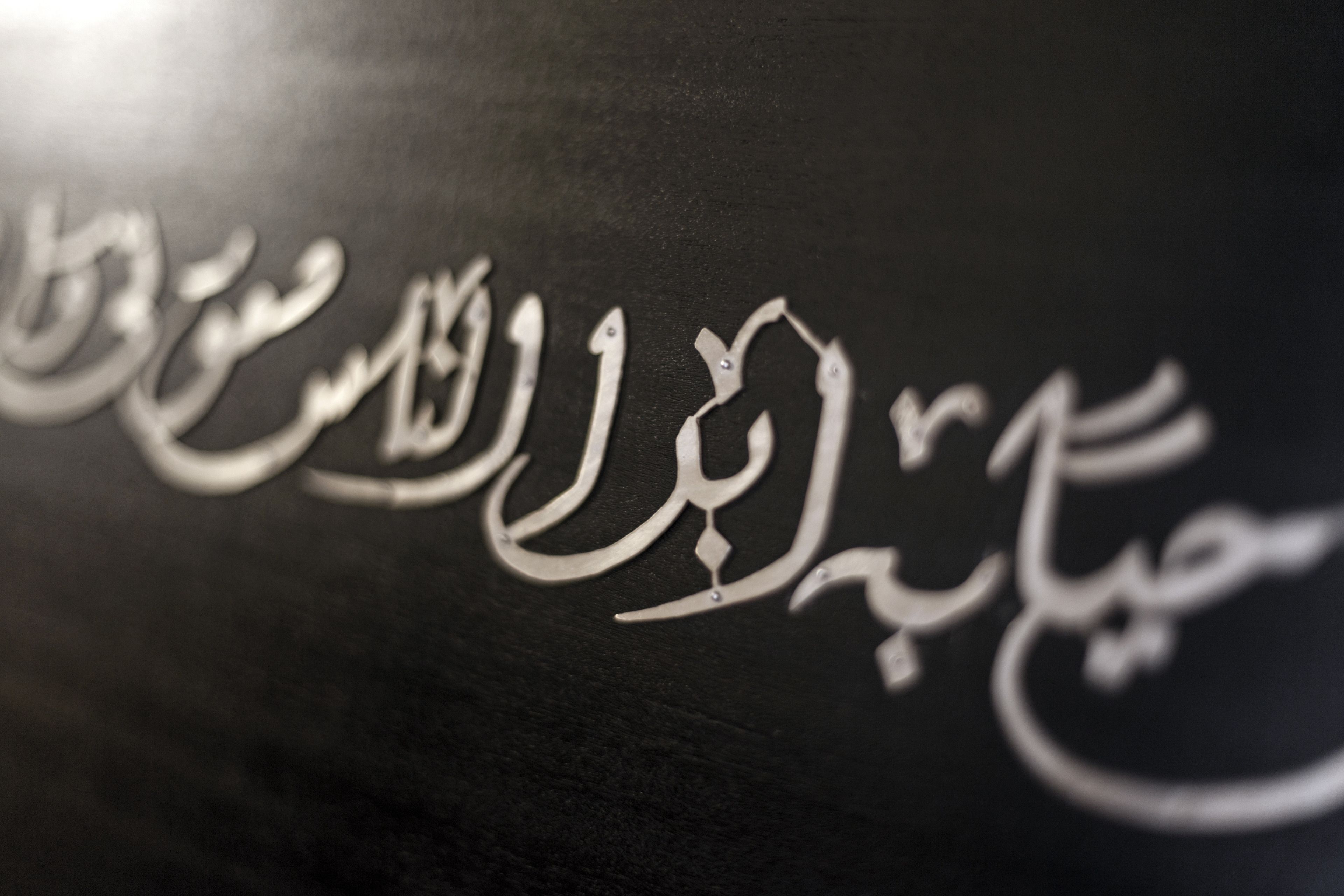 Un dettaglio di calligrafia araba su fondo scuro.