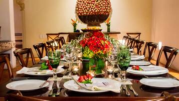 Une table à manger dressée avec de nombreuses assiettes, des verres et des couverts, entourée de chaises.