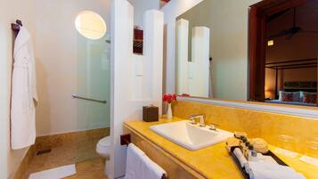 Un baño con encimera de mármol, lavamanos, espejo y zona de ducha.
