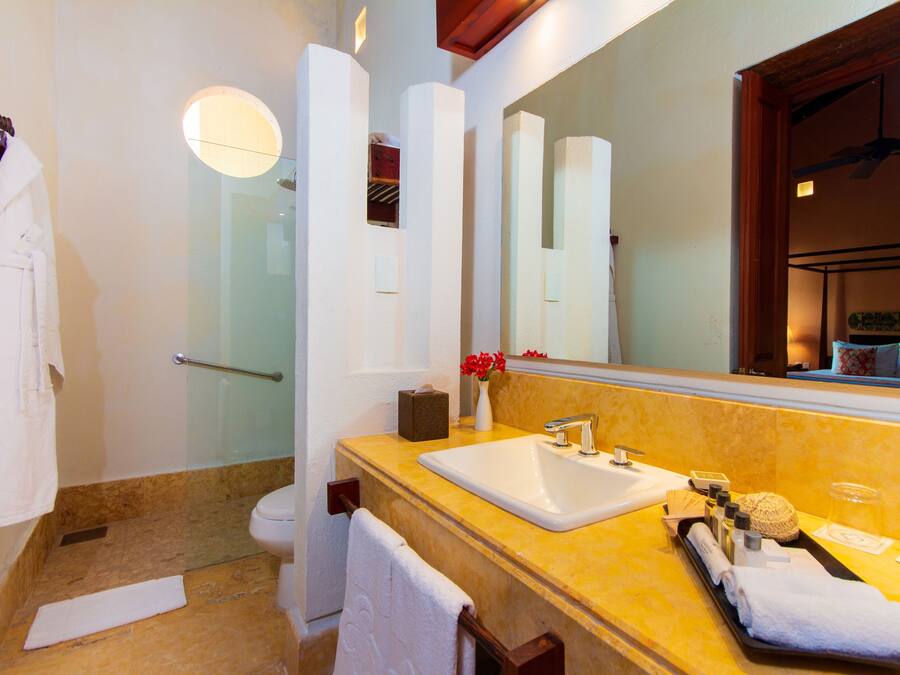Un baño con encimera de mármol, lavamanos, espejo y zona de ducha.
