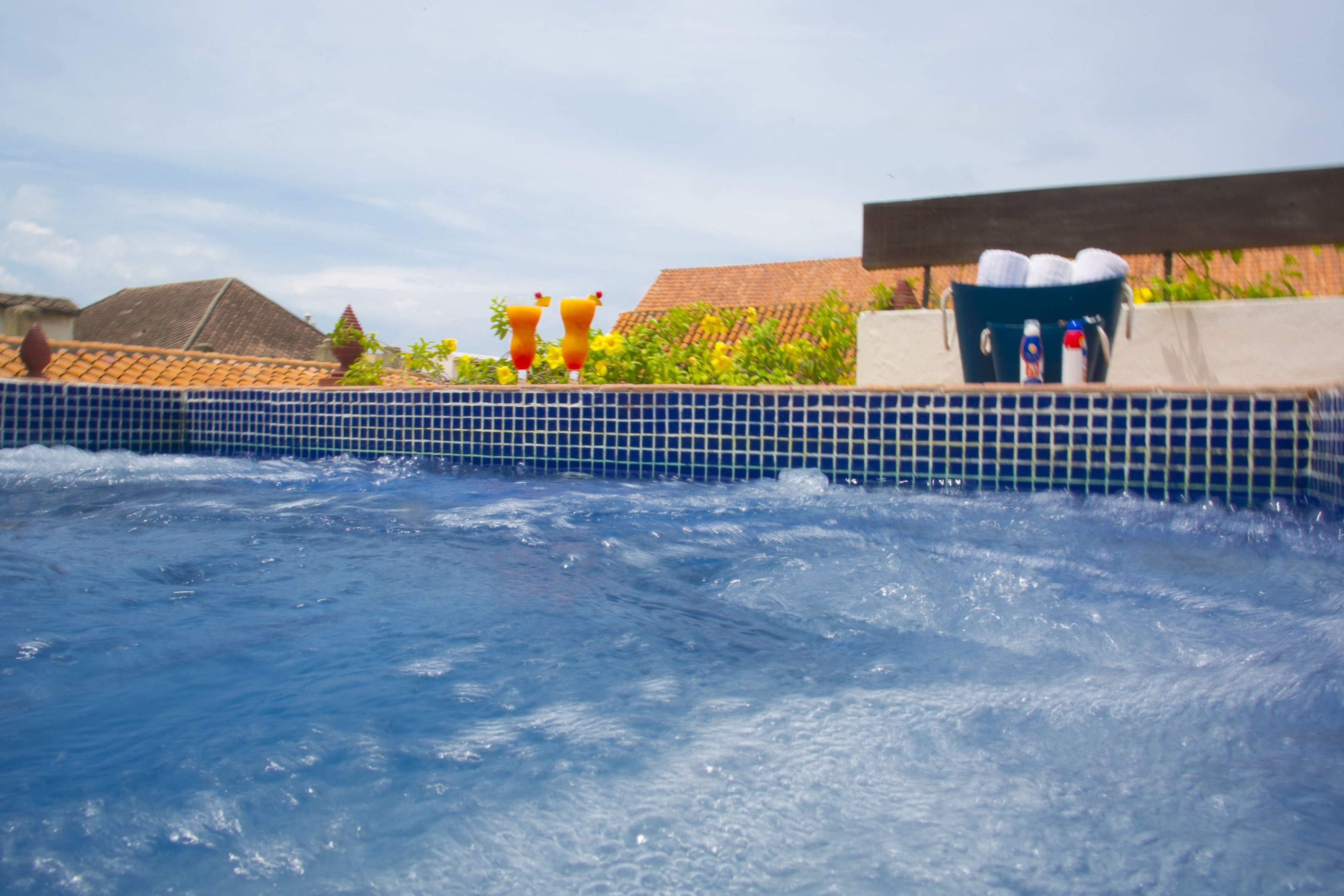 A swimming pool with a tiled edge, a wooden deck, and a view of buildings in the background.