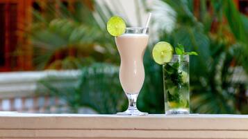 Two drinks on a balcony with a blurred background of greenery and a building.