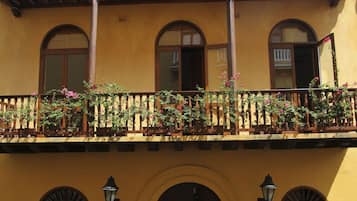 A yellow building with a balcony, arched windows, and a wooden door.