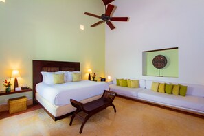 A hotel room with a bed, a sofa, a wooden bench, a ceiling fan, and wall-mounted artwork. - Hotel Quadrifolio (Cartagena)