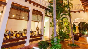 A courtyard with a wooden pergola, palm trees, and potted plants. - Hotel Quadrifolio (Cartagena)