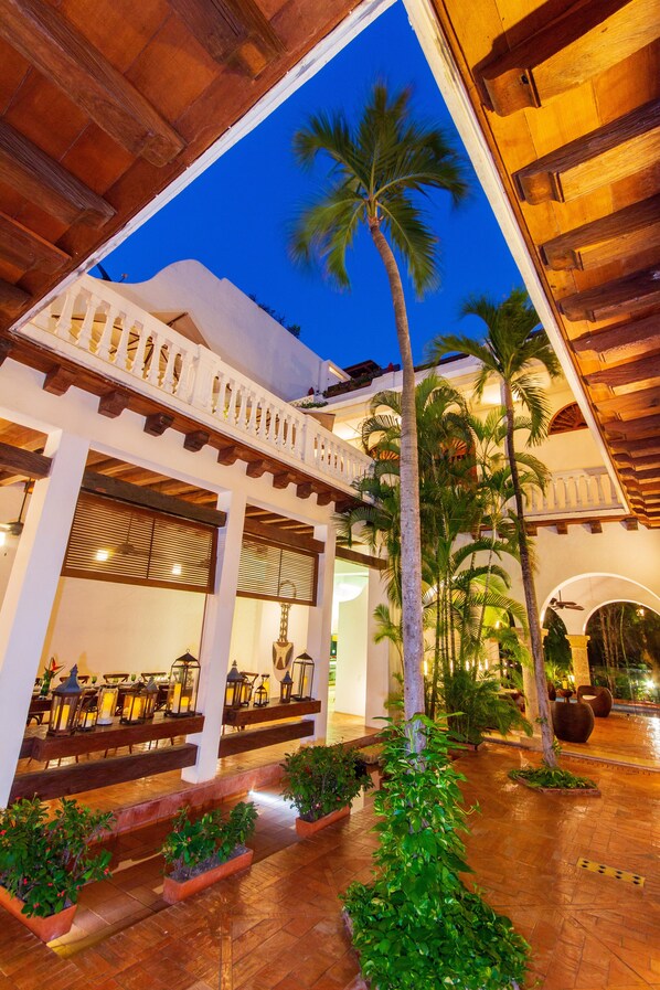 A courtyard with a wooden pergola, palm trees, and potted plants. - Hotel Quadrifolio (Cartagena)