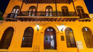 A building with a balcony, arched windows, and a door with a wreath. - Hotel Quadrifolio (Cartagena)