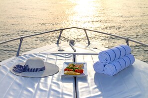 A boat deck with a sun hat, a plate of fruit, and rolled towels. - Hotel Quadrifolio (Cartagena)