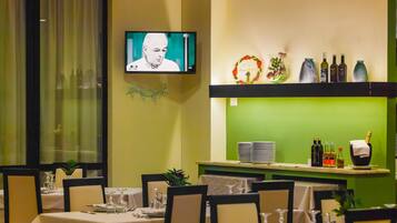 Ein Restaurant mit gedeckten Tischen, einem Fernsehbildschirm und einer Bar mit Flaschen und Gläsern.