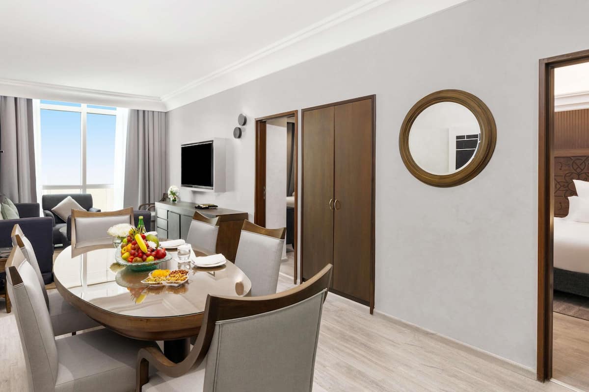 A hotel room with a dining area, a TV, a wardrobe, and a mirror.