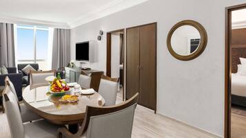 A hotel room with a dining area, a TV, a wardrobe, and a mirror.