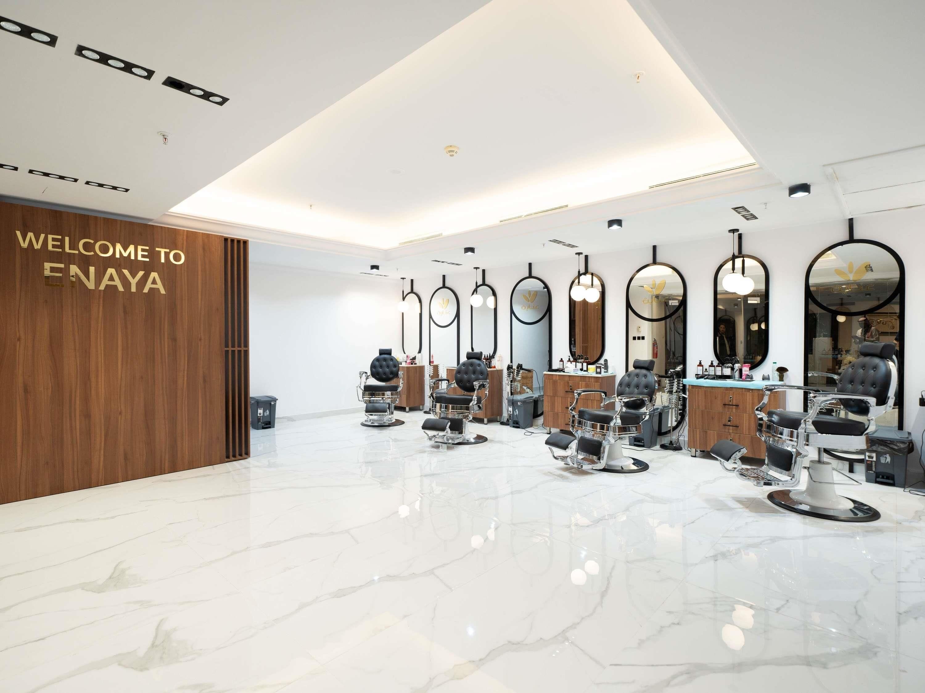 A modern salon interior with multiple barber chairs, mirrors, and a welcoming sign.