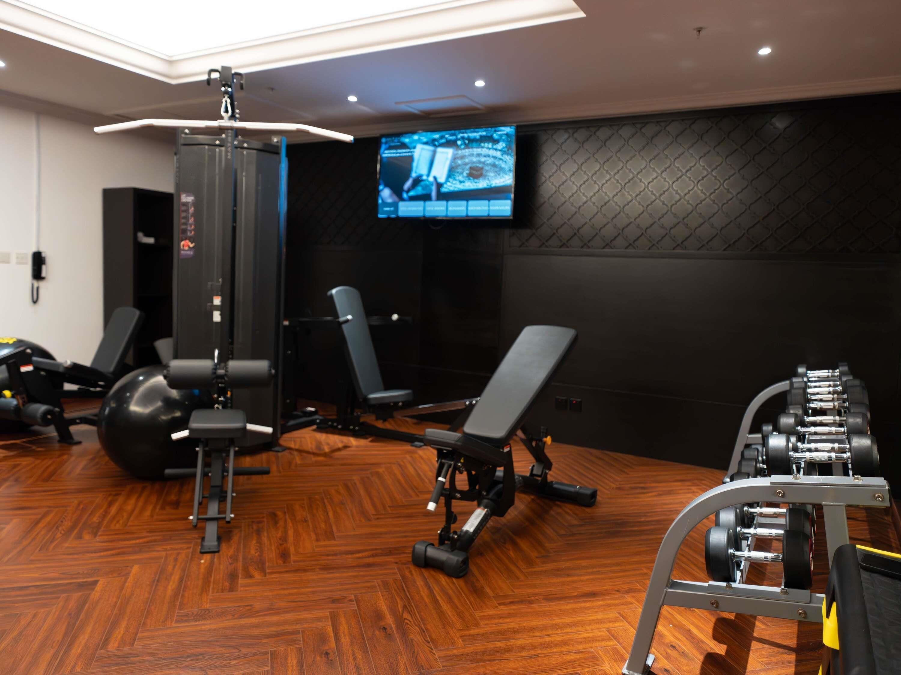 A gym with exercise equipment, a television, and a patterned wall.