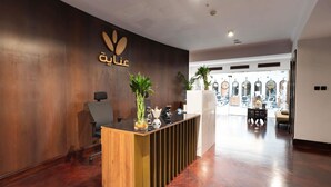 A reception desk with a wooden finish, a potted plant, and a wall-mounted sign.