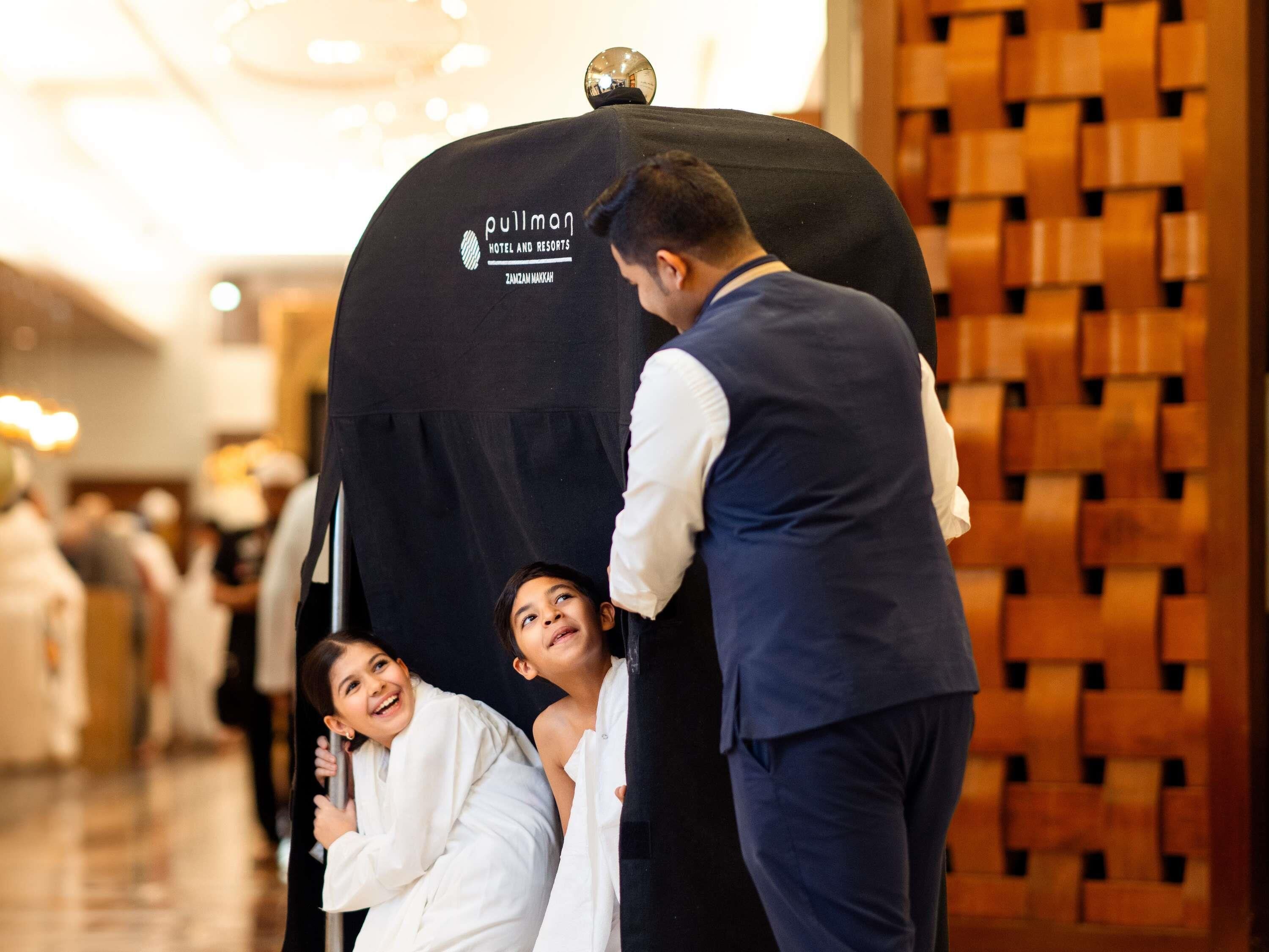 A hotel entrance with a black pullman logo, a wooden wall, and a metal sphere on top.