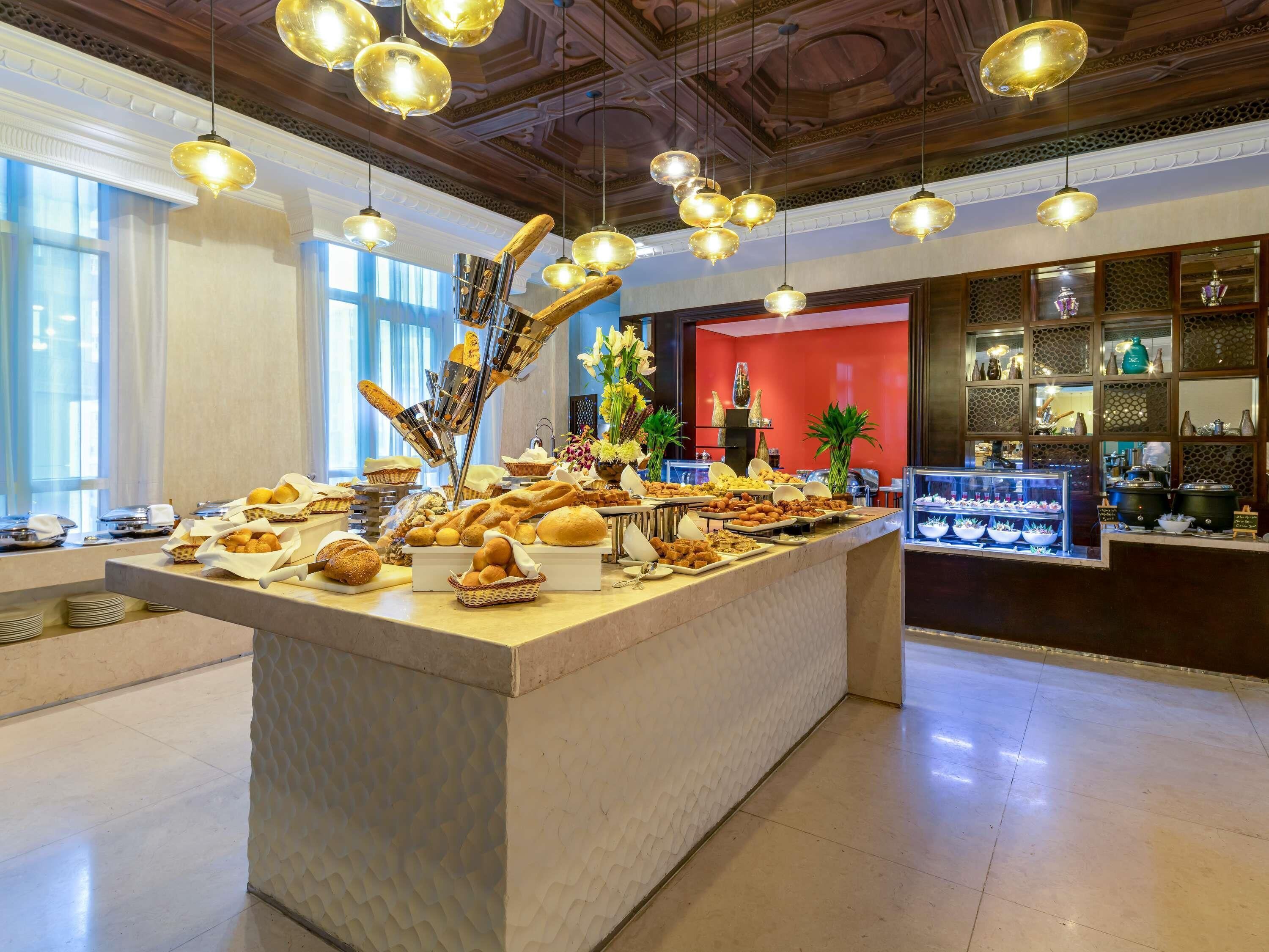 A buffet with various food items, a decorative centerpiece, and a red wall in the background.